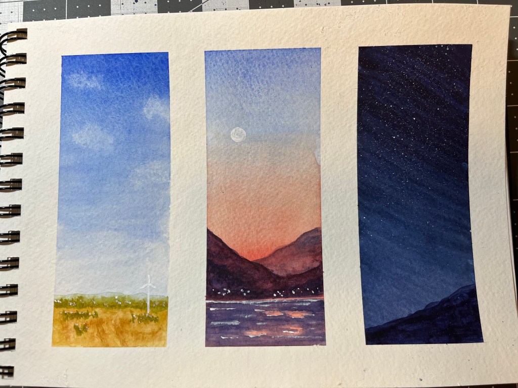 Page in watercolour sketchbook divided into three sections showing a field with windmill, mountains with a sunset, and a night sky with stars