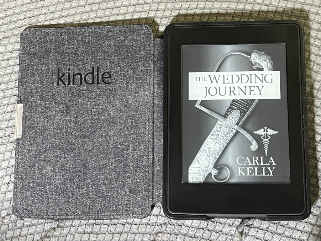 Photo of Kindle showing cover of The Wedding Journey by Carla Kelly